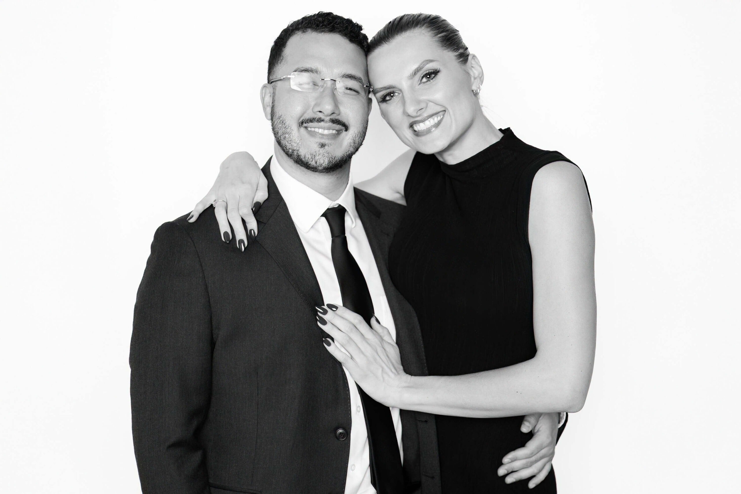 Black-and-white portrait of a smiling couple in formal attire, captured with studio lighting in an editorial Phoenix wedding photo booth.
