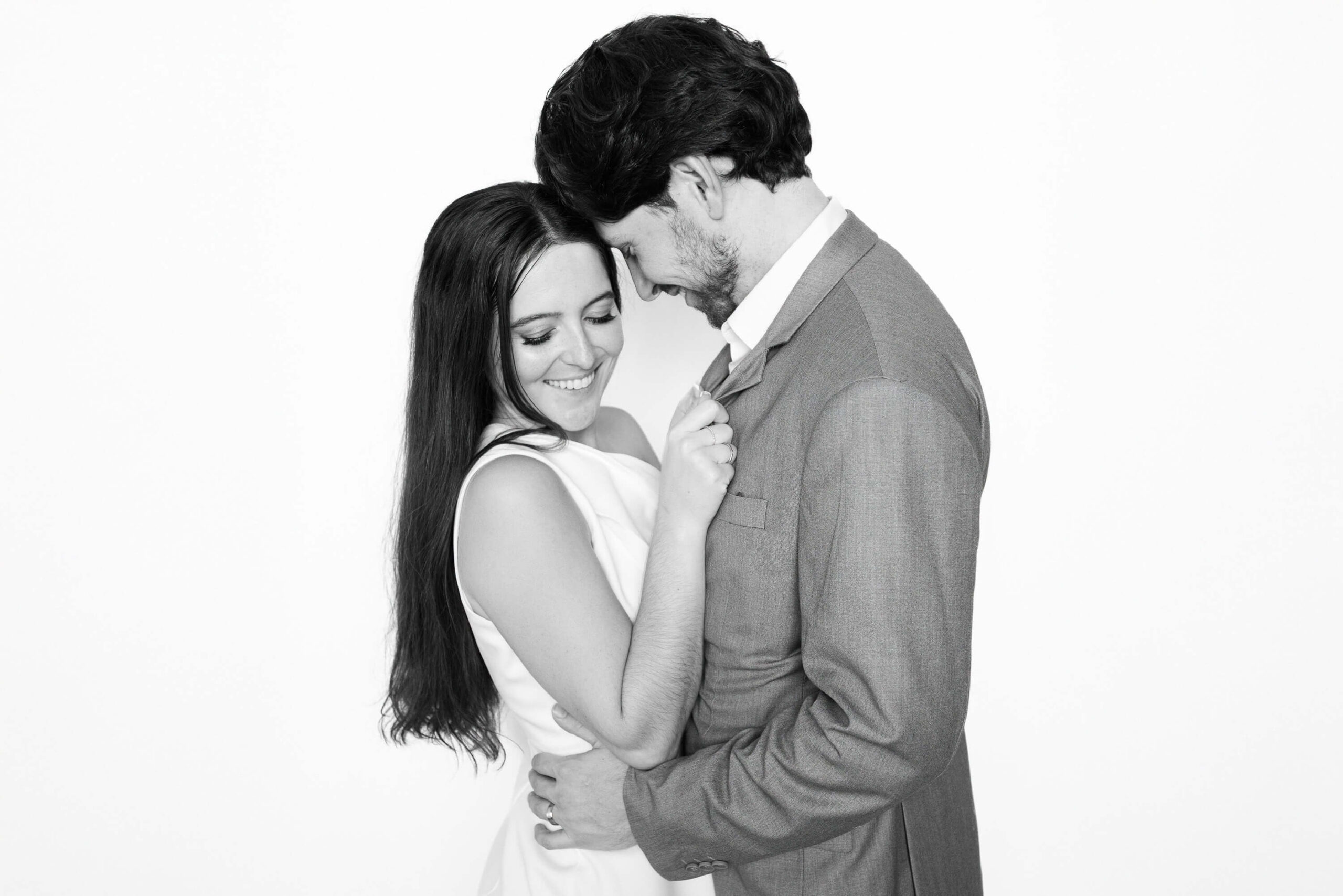 Black-and-white portrait of a couple embracing in elegant attire, photographed with studio lighting inside an editorial Phoenix wedding portrait booth.